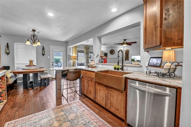 kitchen with dishwasher, ceiling fan with notable chandelier, sink, dark hardwood / wood-style floors, and a kitchen bar