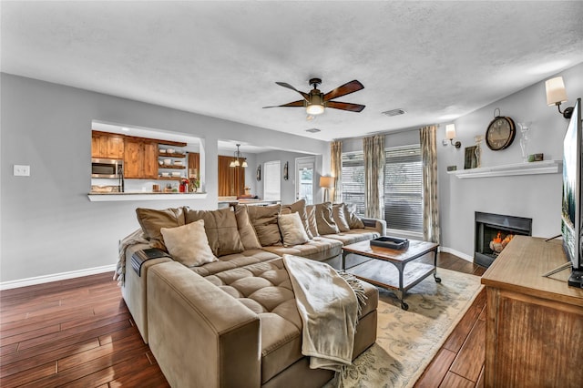 living room featuring a textured ceiling, ceiling fan with notable chandelier, and dark hardwood / wood-style floors