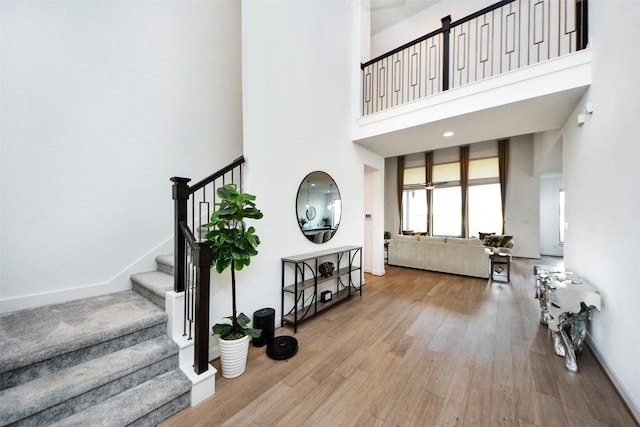 foyer entrance with light wood-type flooring and a towering ceiling