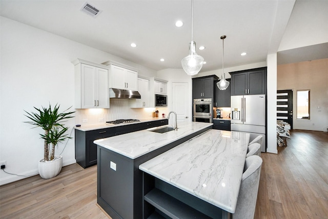 kitchen with hanging light fixtures, sink, an island with sink, appliances with stainless steel finishes, and white cabinetry