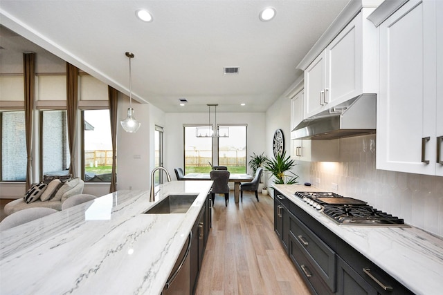 kitchen featuring sink, stainless steel appliances, hanging light fixtures, decorative backsplash, and white cabinets