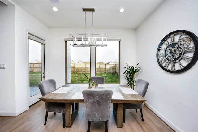 dining room with plenty of natural light, an inviting chandelier, and light wood-type flooring