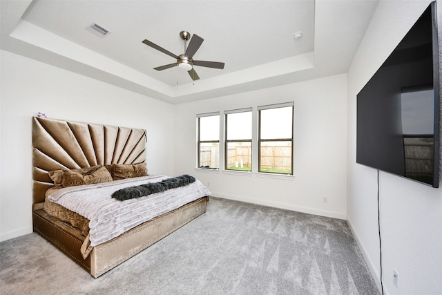 bedroom featuring ceiling fan, a raised ceiling, and light carpet