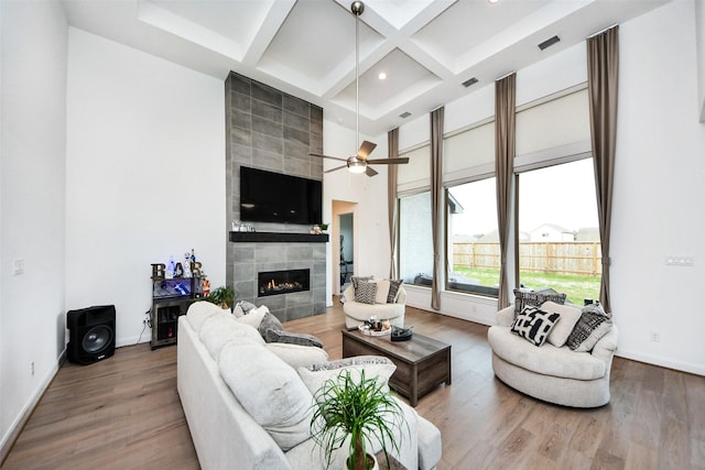 living room featuring ceiling fan, coffered ceiling, a towering ceiling, wood-type flooring, and a fireplace