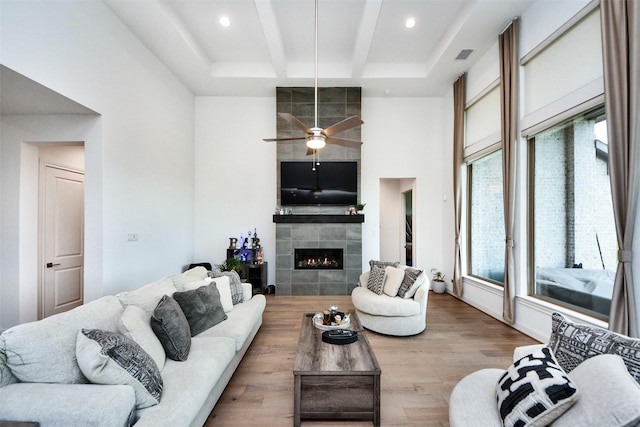 living room featuring a tile fireplace, ceiling fan, a wealth of natural light, and light wood-type flooring