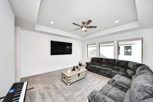 living room featuring a raised ceiling, ceiling fan, and carpet