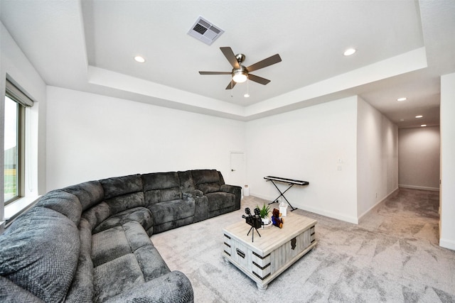 living room featuring light colored carpet, a raised ceiling, and ceiling fan