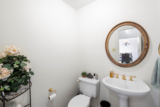 bathroom with a notable chandelier, sink, and toilet