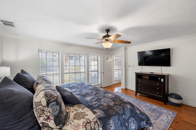 bedroom with a textured ceiling, wood-type flooring, ornamental molding, and ceiling fan