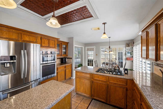 kitchen featuring tasteful backsplash, hanging light fixtures, light tile patterned floors, stainless steel appliances, and light stone countertops