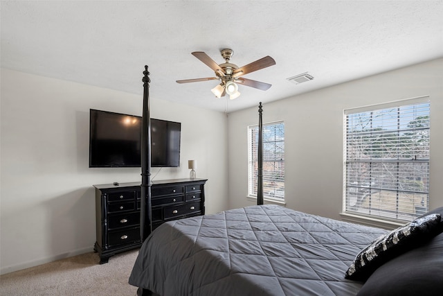 bedroom featuring ceiling fan, light colored carpet, and a textured ceiling