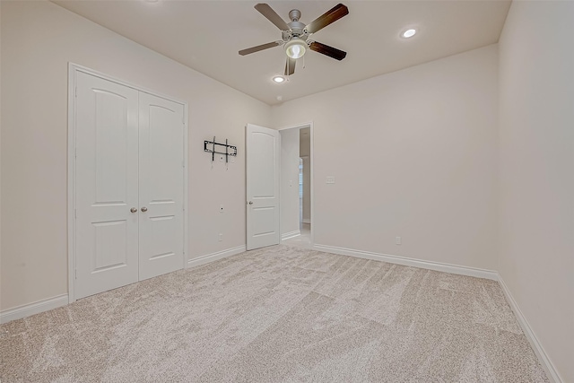 unfurnished bedroom featuring light carpet, a closet, and ceiling fan