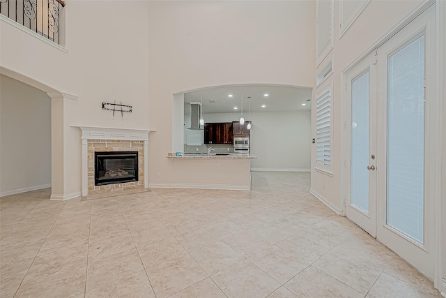 unfurnished living room with a fireplace, a towering ceiling, and light tile patterned flooring