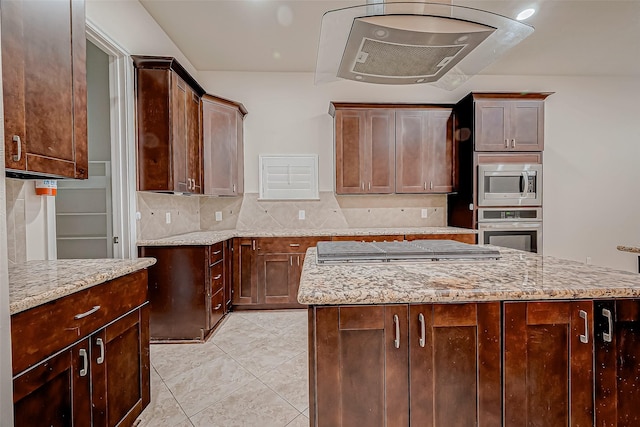 kitchen featuring stainless steel appliances, light stone counters, backsplash, dark brown cabinets, and light tile patterned floors