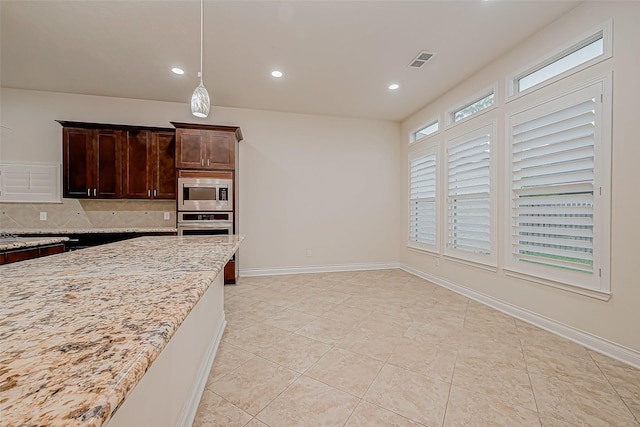 kitchen featuring appliances with stainless steel finishes, tasteful backsplash, light stone counters, dark brown cabinetry, and hanging light fixtures