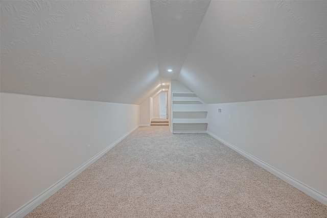 bonus room with light colored carpet, a textured ceiling, and vaulted ceiling