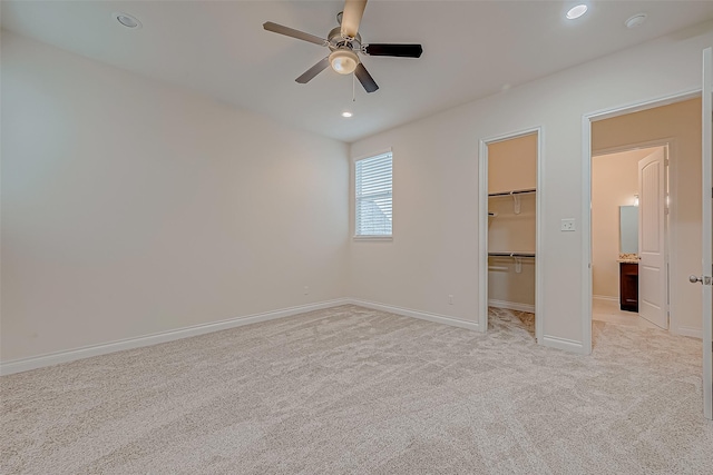 unfurnished bedroom featuring a walk in closet, ceiling fan, a closet, and light carpet