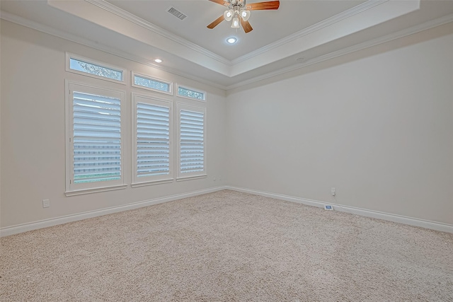 carpeted empty room featuring ceiling fan, a raised ceiling, and ornamental molding