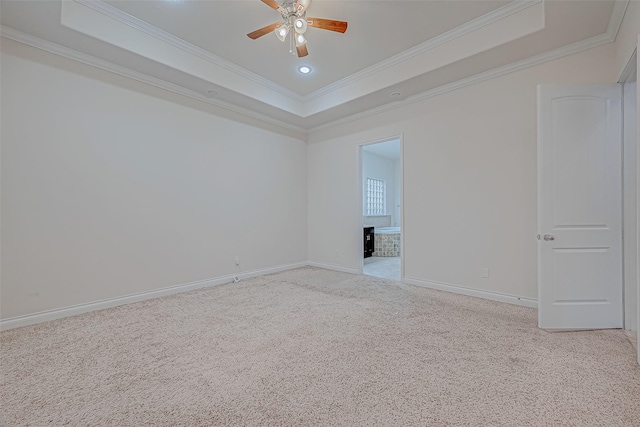 carpeted spare room featuring a brick fireplace, ceiling fan, ornamental molding, and a tray ceiling