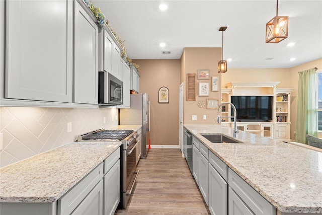 kitchen with backsplash, sink, gray cabinets, decorative light fixtures, and stainless steel appliances