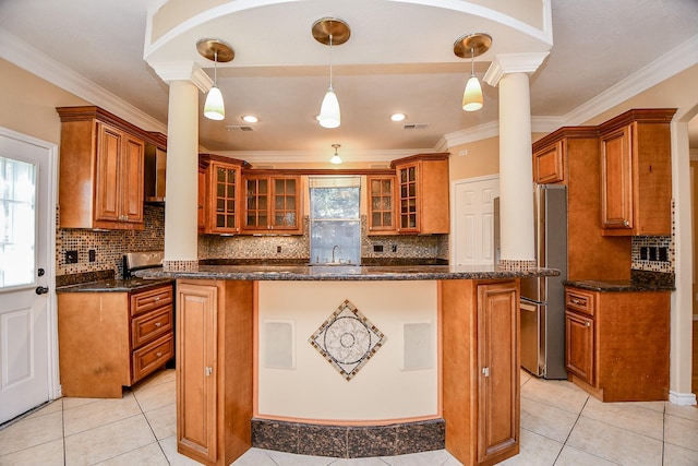 kitchen featuring pendant lighting, crown molding, dark stone countertops, stainless steel refrigerator, and decorative columns