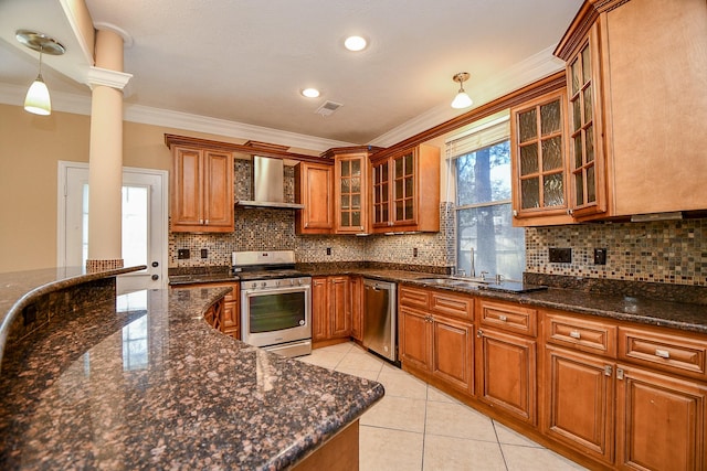 kitchen with pendant lighting, crown molding, wall chimney exhaust hood, appliances with stainless steel finishes, and light tile patterned flooring