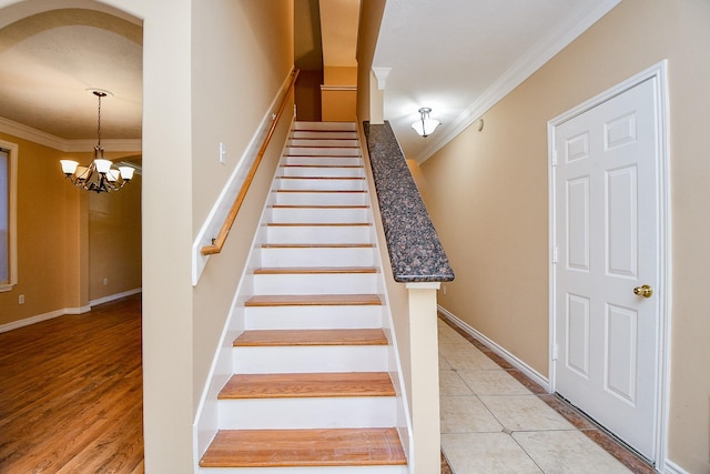 stairway featuring tile patterned floors, crown molding, and an inviting chandelier