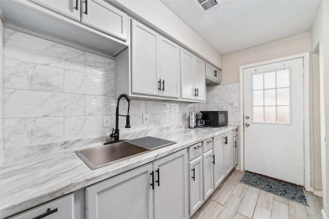 kitchen with light stone countertops, tasteful backsplash, and sink