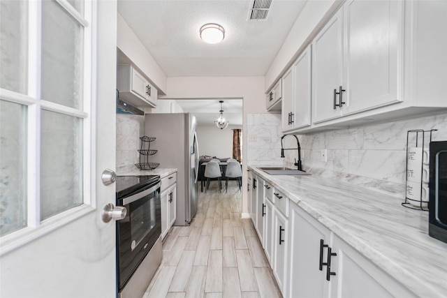 kitchen featuring black / electric stove, white cabinetry, sink, and light stone countertops