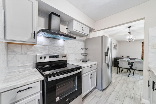 kitchen featuring white cabinetry, hanging light fixtures, wall chimney range hood, backsplash, and appliances with stainless steel finishes