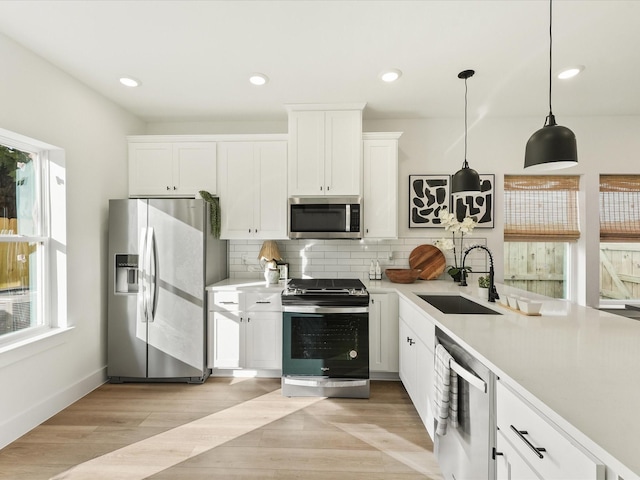 kitchen featuring sink, backsplash, pendant lighting, white cabinets, and appliances with stainless steel finishes