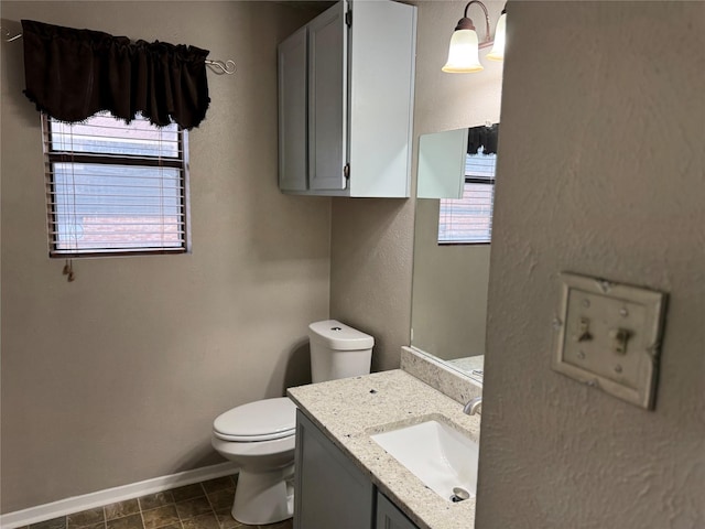 bathroom featuring a wealth of natural light, vanity, and toilet