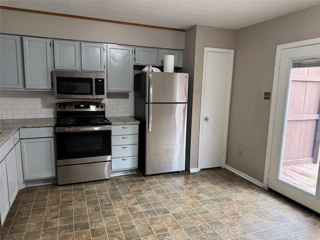 kitchen featuring appliances with stainless steel finishes, a textured ceiling, gray cabinets, and tasteful backsplash