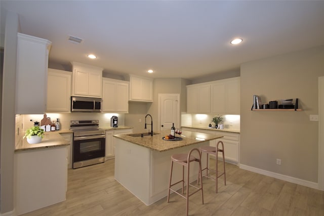 kitchen with white cabinetry, a kitchen island with sink, sink, and appliances with stainless steel finishes