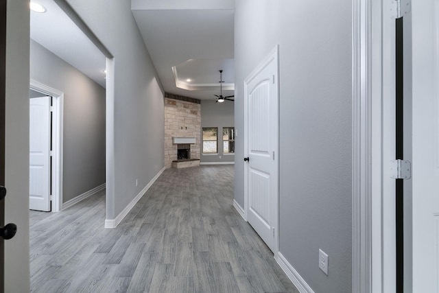 corridor with a tray ceiling and light hardwood / wood-style flooring