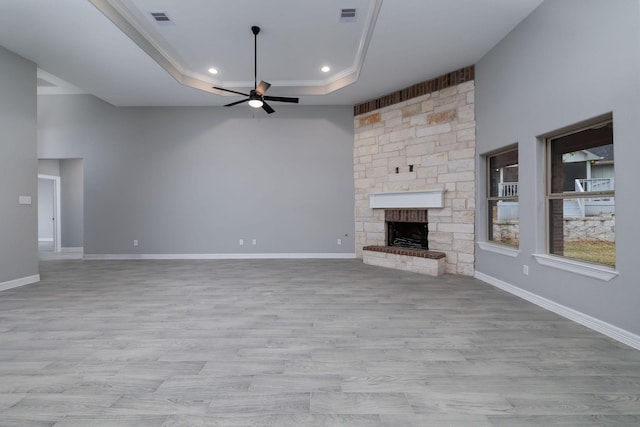 unfurnished living room with ceiling fan, ornamental molding, a fireplace, and a tray ceiling