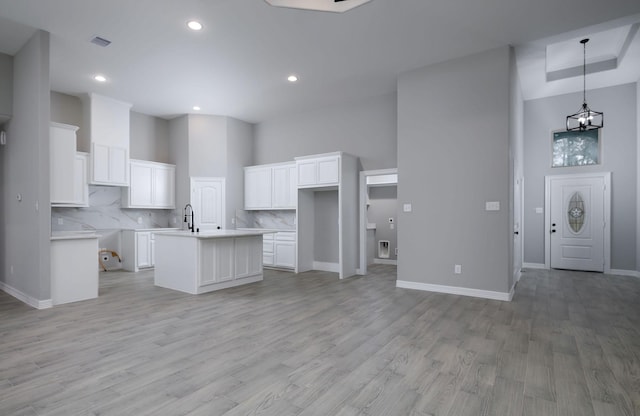 kitchen with white cabinetry, a kitchen island with sink, and a high ceiling