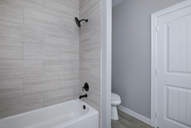 bathroom featuring tiled shower / bath combo, toilet, and wood-type flooring