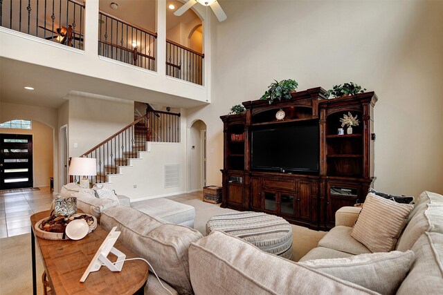 living room with a towering ceiling, ceiling fan, and light tile patterned flooring