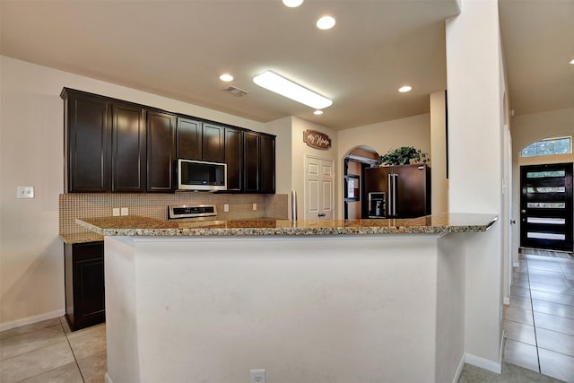 kitchen with kitchen peninsula, stainless steel appliances, and light stone counters