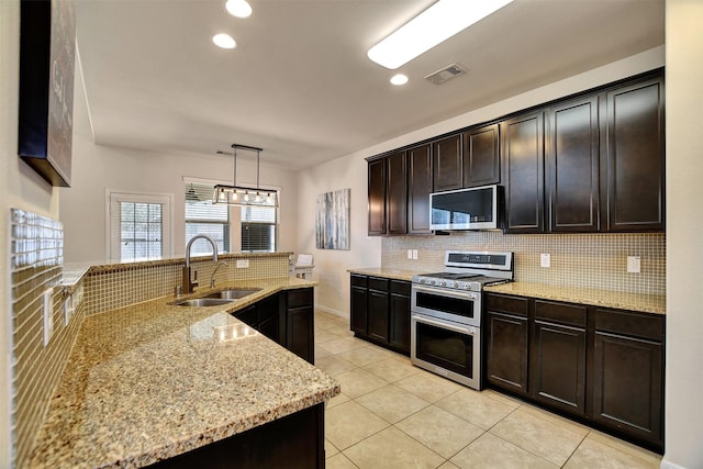 kitchen featuring light stone countertops, dark brown cabinetry, stainless steel appliances, sink, and hanging light fixtures