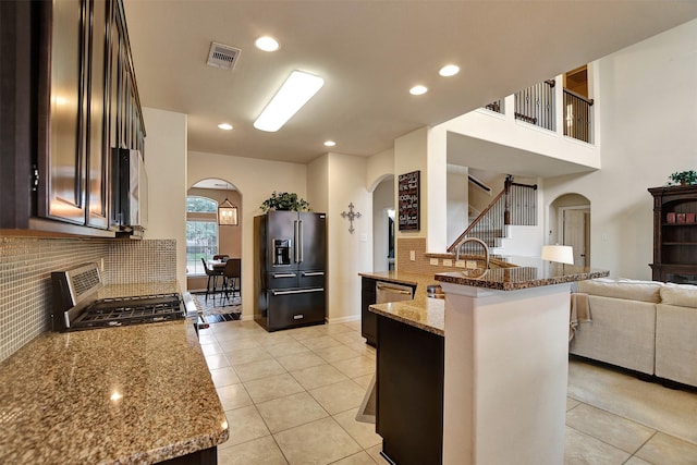 kitchen with stove, light stone countertops, tasteful backsplash, high end fridge, and a kitchen bar