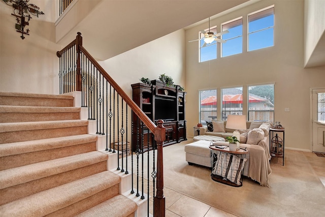 tiled living room with ceiling fan and a high ceiling