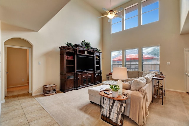 living room with ceiling fan, a towering ceiling, and light tile patterned floors