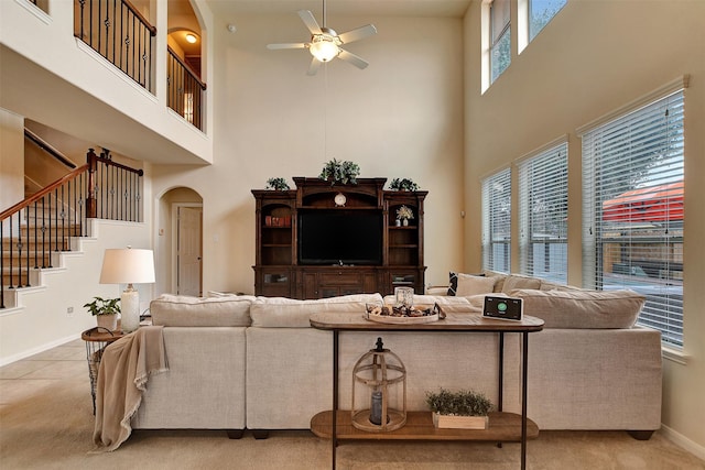 carpeted living room featuring a wealth of natural light, a towering ceiling, and ceiling fan