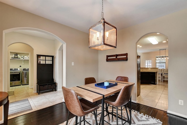 dining room with independent washer and dryer, light hardwood / wood-style flooring, and a notable chandelier