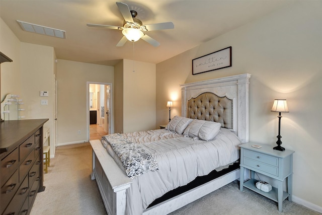 bedroom featuring ceiling fan, ensuite bathroom, and light colored carpet