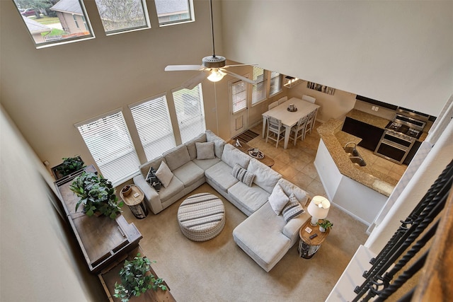 living room with tile patterned floors, a wealth of natural light, ceiling fan, and a high ceiling