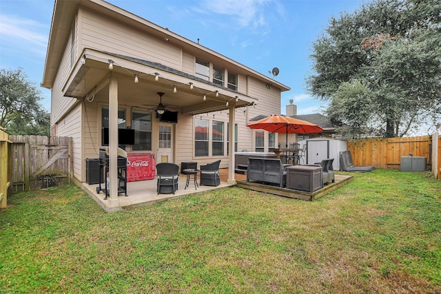 back of property featuring a lawn, a jacuzzi, ceiling fan, a shed, and a patio