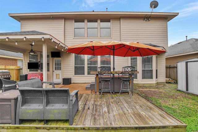 wooden terrace with area for grilling, ceiling fan, and a storage shed